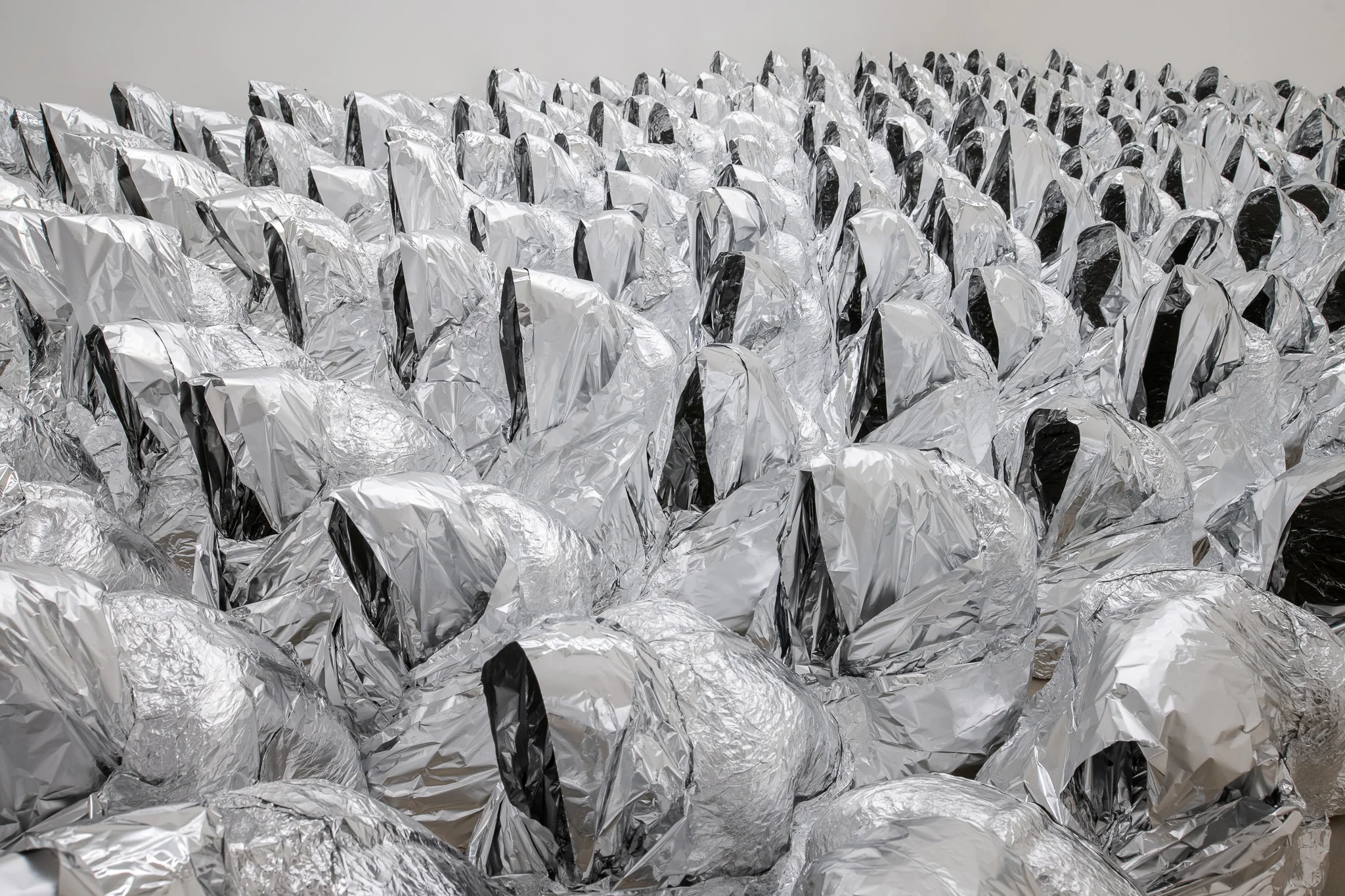 Kader Attia, Ghost, 2007/2024. Installation: life-size figures, aluminum foil, Dimension variable. Exhibition copy.Photo: Swita Uancharoenkul. Courtesy of the Jim Thompson Art Center and the James H.W. Thompson Foundation © Jim Thompson Art Center
